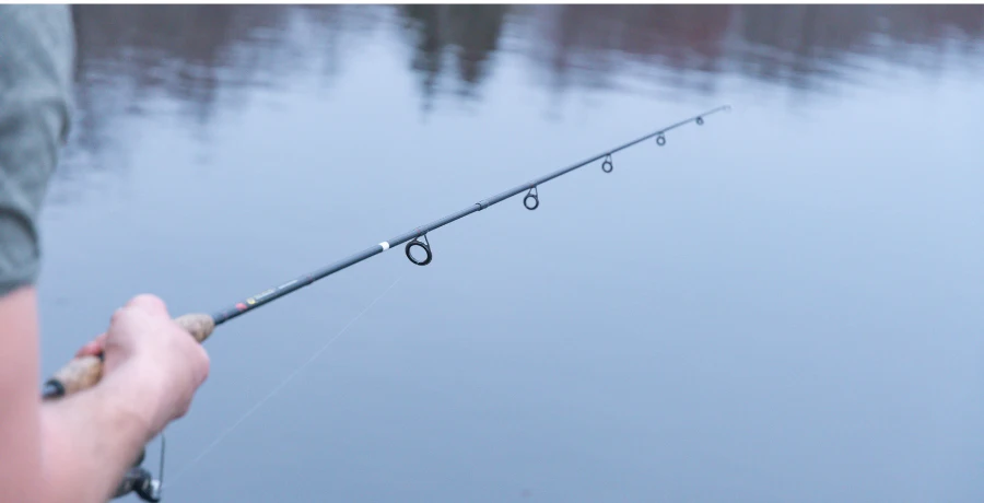 Gäddfiske i Sverige med ett modernt fiskespö för gädda – närbild på spö riktat mot vattenytan, perfekt för kast med stora beten.