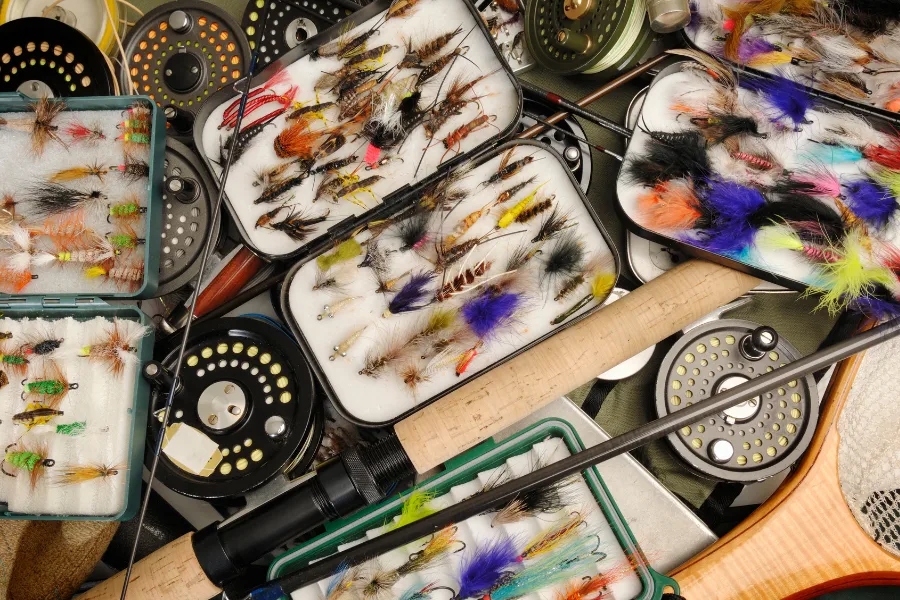 Samling av flugfiskeutrustning – färgglada flugor i askar, flugspön och fiskerullar för sportfiske.