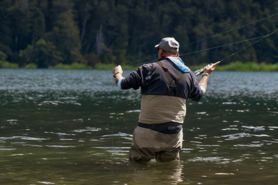 Flugfiskare i vadarbyxor står i sjön och kastar med flugspö.